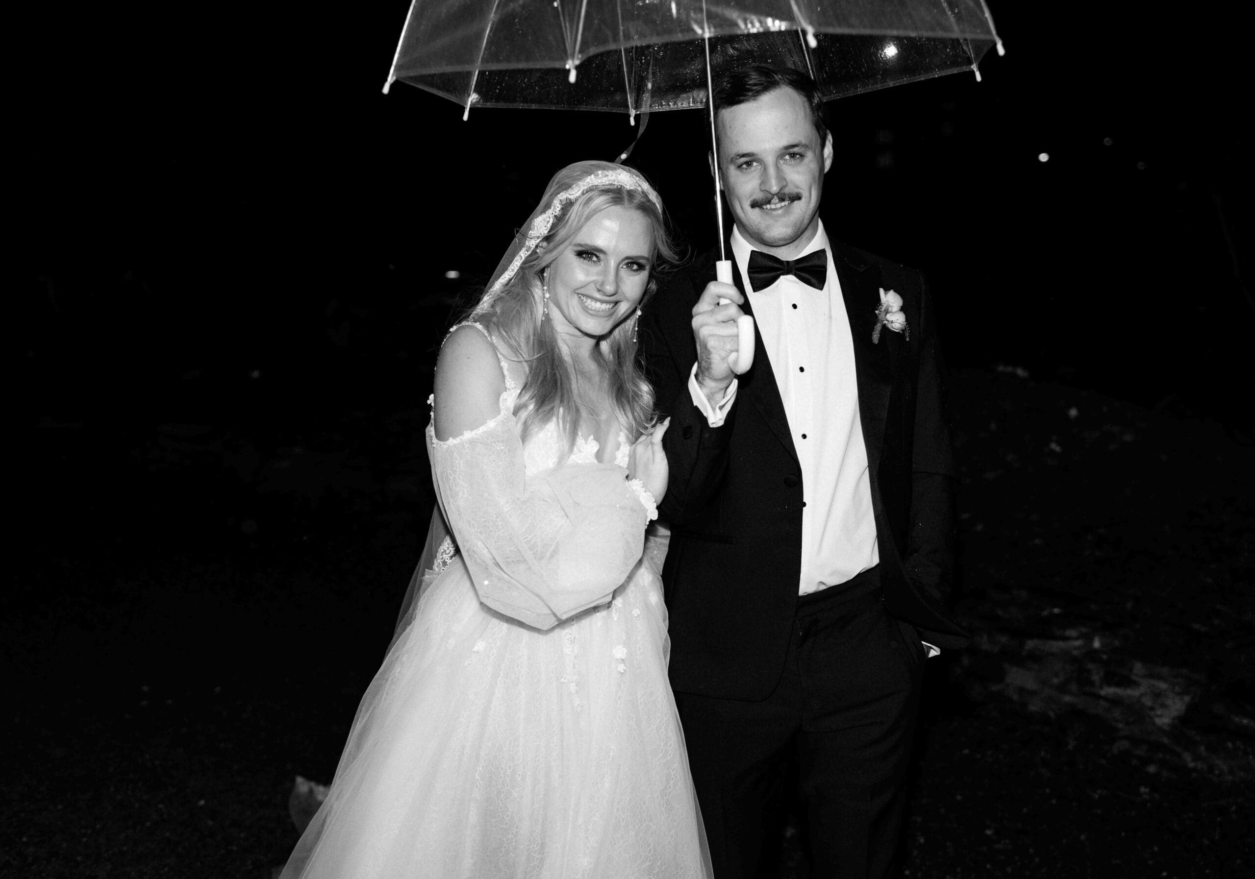 bride and groom under a clear umbrella for the rain